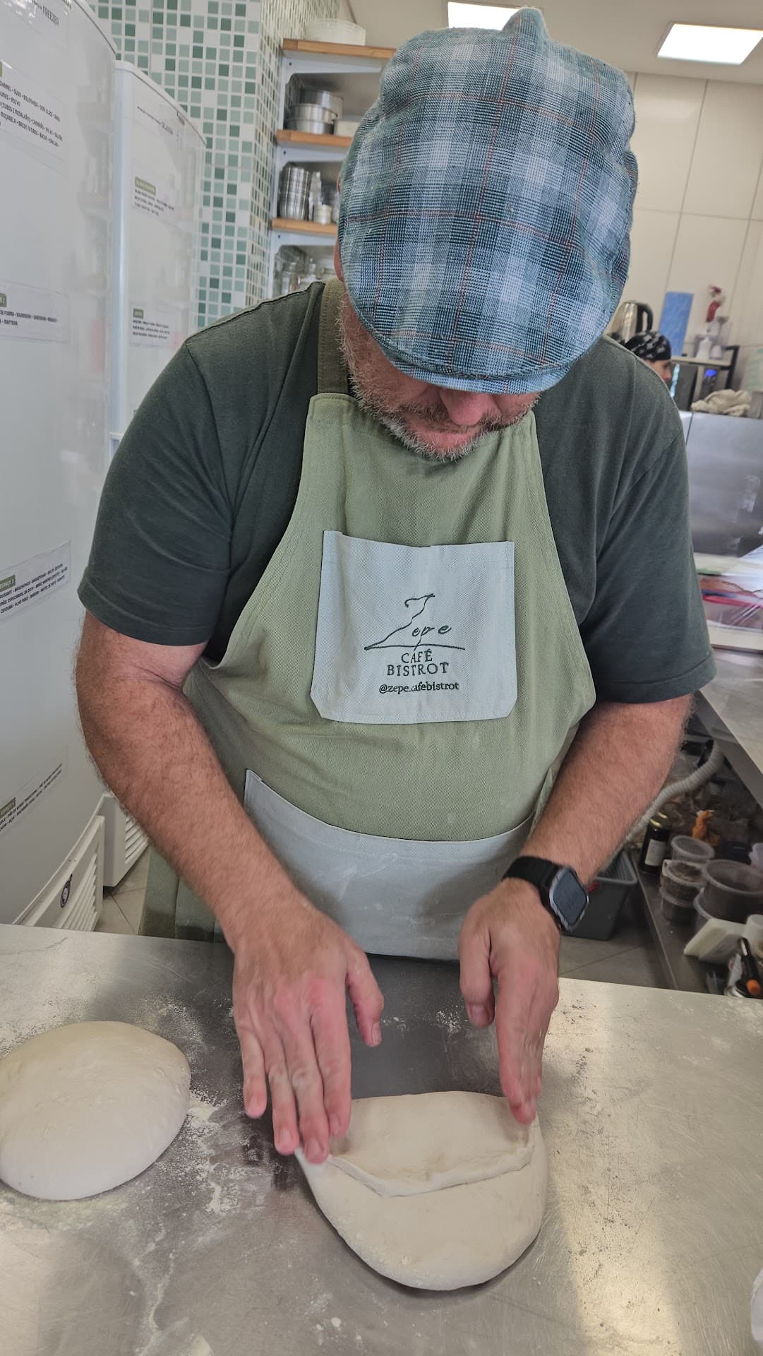 Chef Marcelo modelando a borda de um disco de massa no balcão da cozinha do Zepe, com outra porção de massa descansando ao lado.